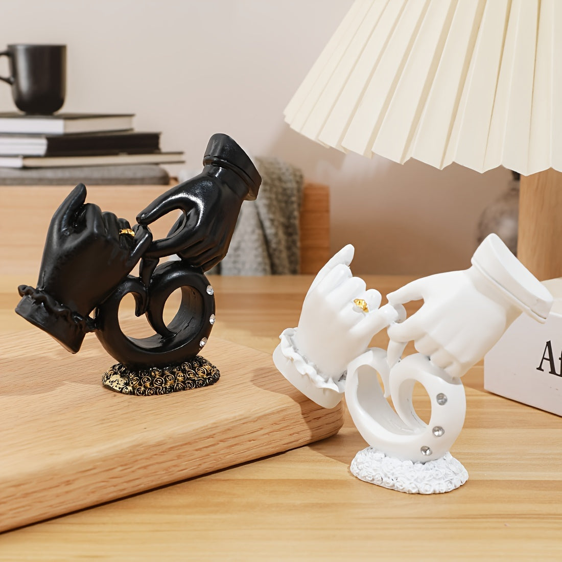 Black and white decorative figurines on a wooden surface with a lamp in the background.
