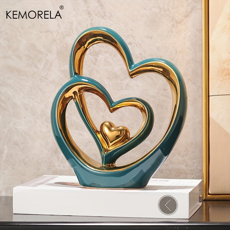 Decorative sculpture of interlocking hearts in teal and gold on a white base with KEMORELA branding.