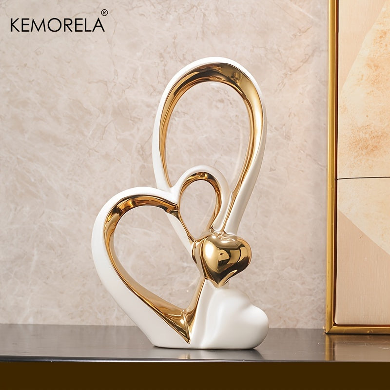 Decorative sculpture of two interlocking hearts, one gold and one white, on a neutral background with 'KEMORELA' branding.