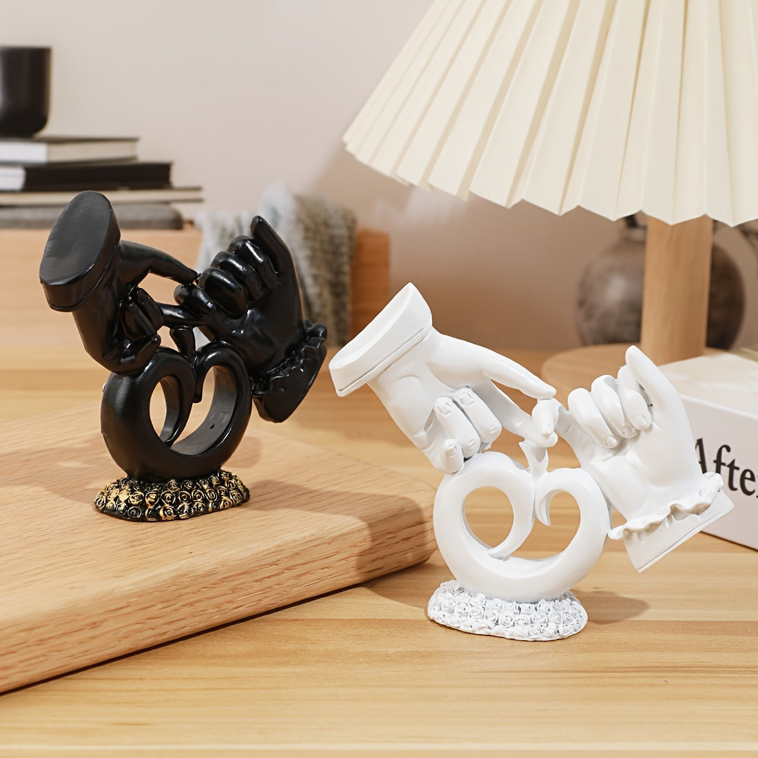 Black and white decorative figurines on a wooden surface with a lamp in the background.
