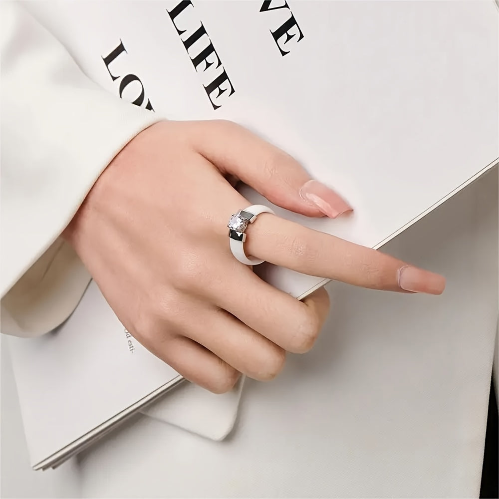 Hand wearing a silver ring with a diamond, holding a magazine with visible text.