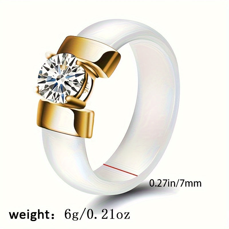 White ceramic ring with gold accents and a clear gemstone on a white background