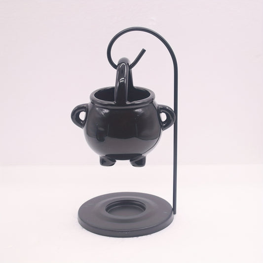 Black cauldron-shaped holder with a candle on a white background